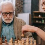 badante che tiene allenata la mente di un anziano facendo con lui giochi come gli scacchi